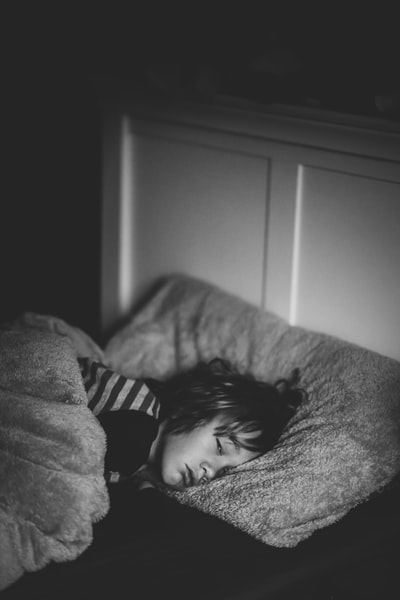 灰度摄影的孩子躺在床上
